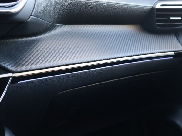 Dashboard in zacht materiaal met carboneffect en hoogglans zwarte sierstrip met chromen bies Dashboard in zacht materiaal met carboneffect en hoogglans zwarte sierstrip met chromen bies