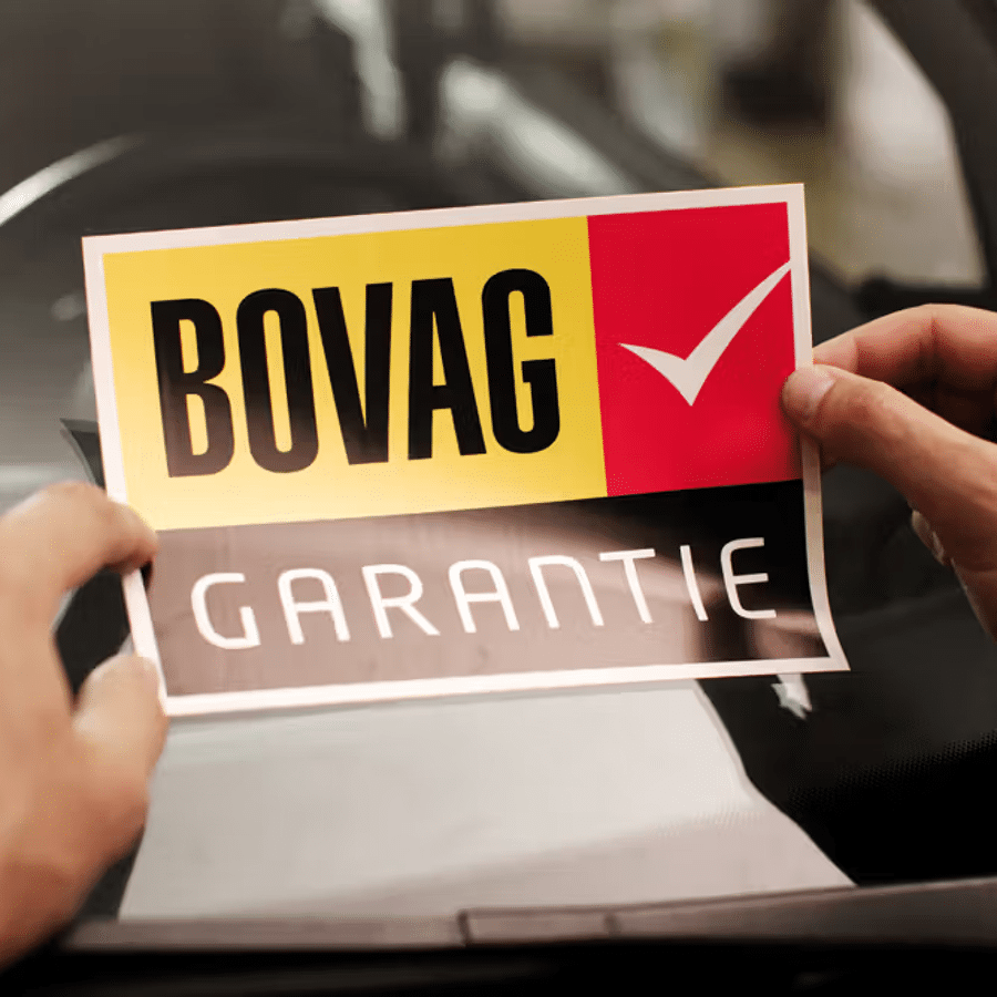 Een sticker met BOVAG Garantie wordt op een autoruit geplakt