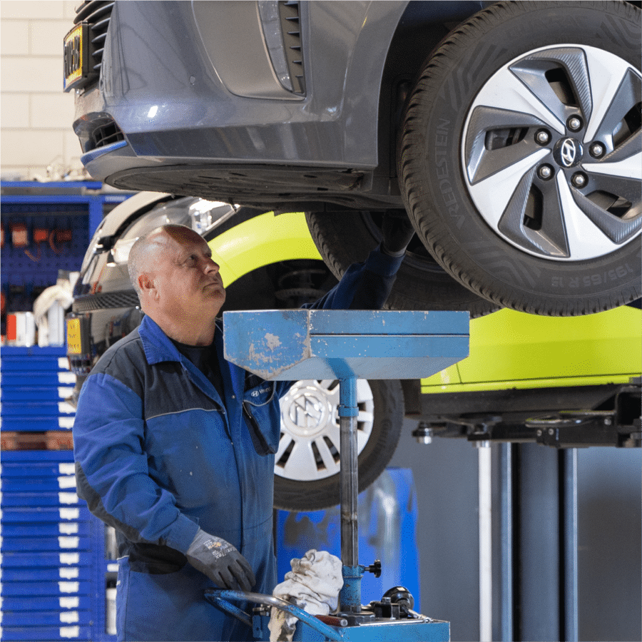 Een automonteur van Autogroep Twente met een Hyundai overall bekijkt de carrosserie van een Hyundai auto op de brug.