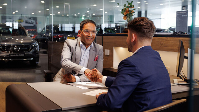 Twee mensen schudden elkaar de hand aan een tafel in de showroom