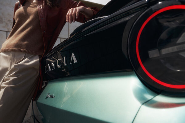 Vrouw leunt op kofferbak van nieuwe Lancia Ypsilon 2024