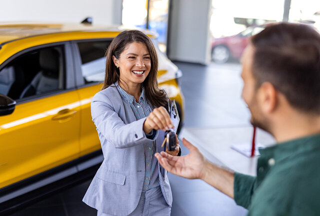 Klant ruilt auto in bij Nefkens en ontvangt de autosleutel van een nieuwe auto in de showroom.
