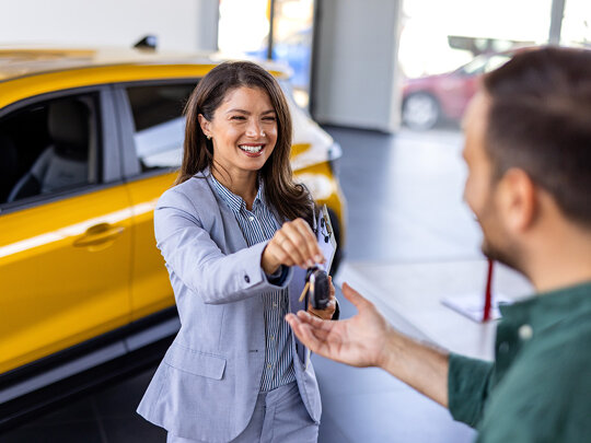 Klant ruilt auto in bij Nefkens en ontvangt de autosleutel van een nieuwe auto in de showroom.