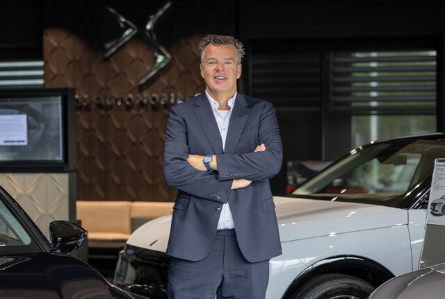 Jeroen de Bruijn, occasionmanager bij Nefkens, staat met gekruiste armen naast een auto in de showroom.